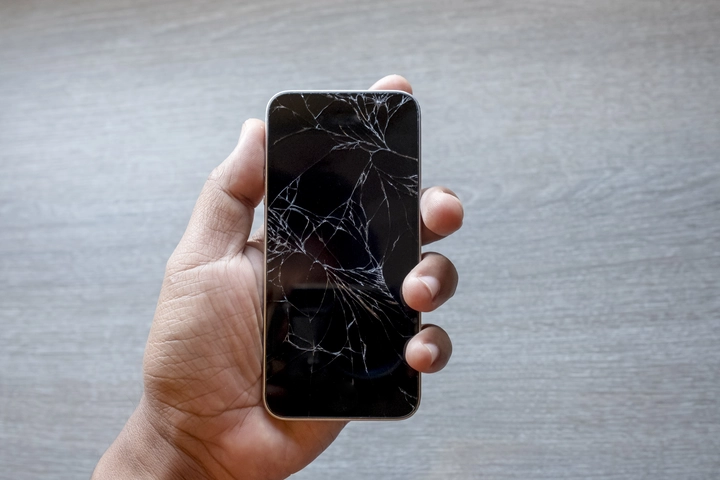手持螢幕破裂的 iPhone，適合說明屏東手機螢幕維修情境
